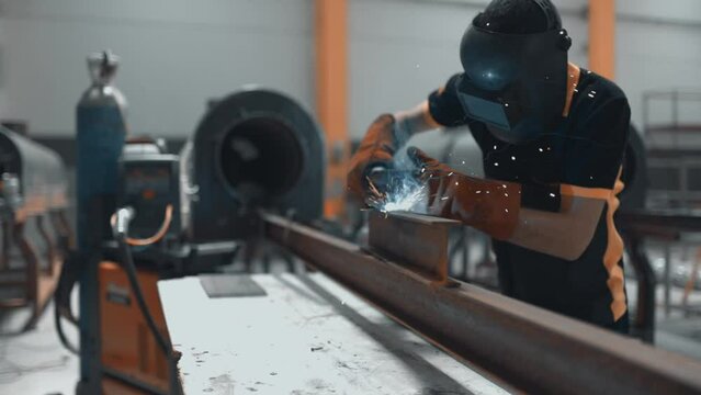 Professional Heavy Industry Welder Working In Industrial Production Factory. Welding Worker Wearing Helmet. Industrial Process, Heat Electrode Work. Metalwork Assembly, Construction