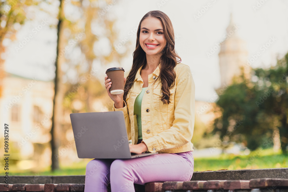 Sticker portrait of beautiful cheerful brown-haired girl sitting outside drinking latte using laptop working