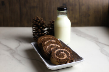 chocolate roll cake filled with cream on wooden table