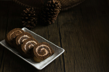 chocolate roll cake filled with cream on wooden table