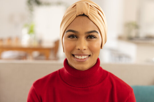 Close-up portrait of smiling biracial young woman wearing headscarf at home