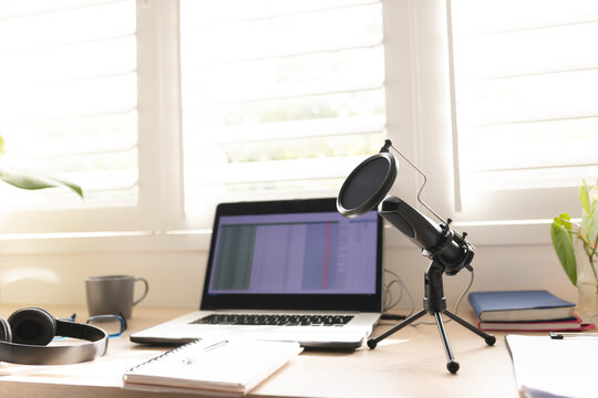 Condenser microphone with laptop on table by window at home studio