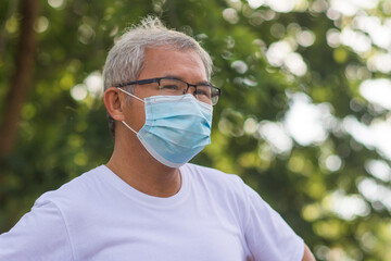 Old Asian man walking exercise outdoor and wearing medical mask