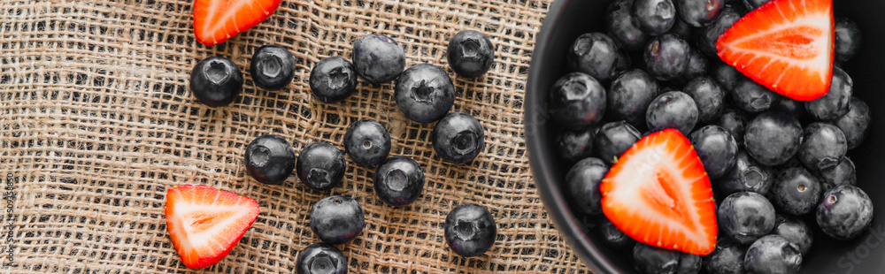 Poster Top view of natural berries near bowl on sackcloth, banner.