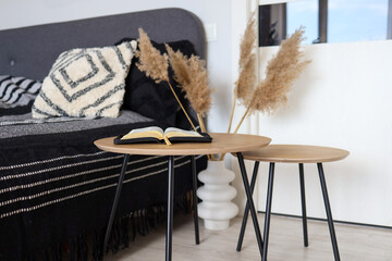 Open bible on wooden table in bedroom, scandinavian interior