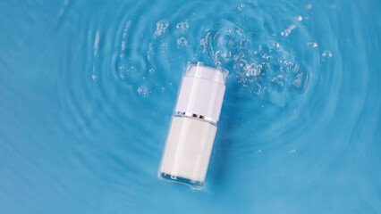 Mockup of a jar of moisturizing cream in water with drops and a blue background.