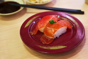 Marinated Tuna with soy sauce Sushi or Marinated Maguro with Shoyu Sushi, Sushi on a round plate on the table in the restaurant. Close-up image of Japanese food.