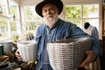 Happy aged man selling wicker products in shop