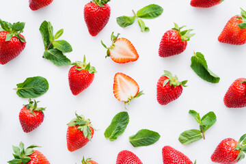 Top view of fresh strawberries and mint leaves on white background.