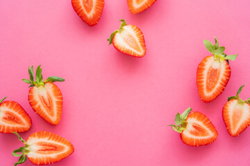 Flat lay with strawberries with green leaves on pink background.