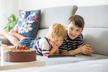 Toddler boy and older brother, watching movie on tablet at home