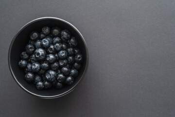 Top view of blueberries in bowl on black background.