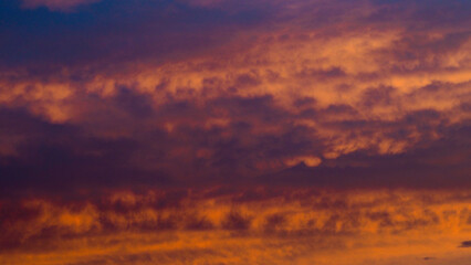 De magnifiques teintes orangées colorent le ciel du crépuscule, sous des nuages de moyenne...