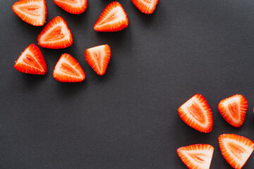 Top view of tasty cut strawberries on black background.