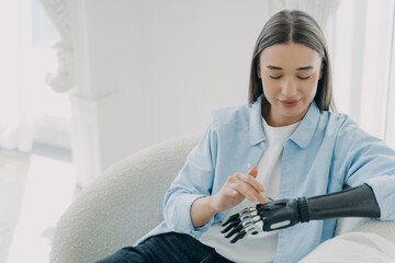 Happy handicapped girl is setting up her artificial limb and pressing buttons. Copy space.