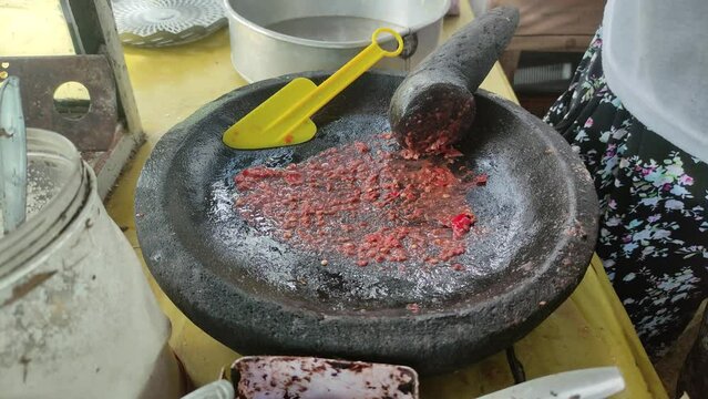 A merchant is mixing rujak spices. Rujak is a typical Indonesian food, consisting of fresh fruits and spicy spices.