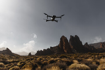 Fototapeta na wymiar Folding small drone is flying over the mountains.