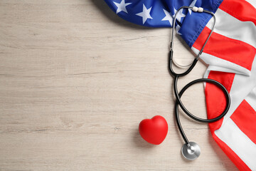 Stethoscope, red heart and American flag on white wooden table, flat lay. Space for text © New Africa