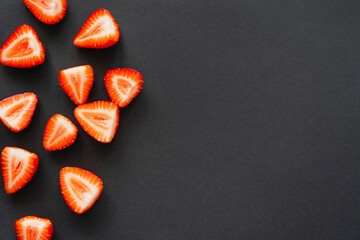 Top view of juicy cut berries on black background with copy space.