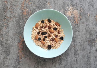 Bowl of raw, whole oatmeal with raisins and almonds nuts