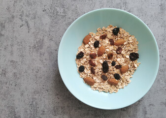 Bowl of raw, whole oatmeal with raisins and almonds nuts