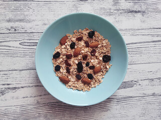 Bowl of raw, whole oatmeal with raisins and almonds nuts
