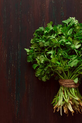 bunch of fresh Cilantro, on a brown wooden table, close-up, top view, no people.