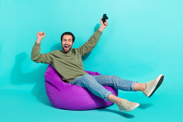 Full body profile side photo of young man sit purple chair celebrate victory competition isolated over turquoise color background