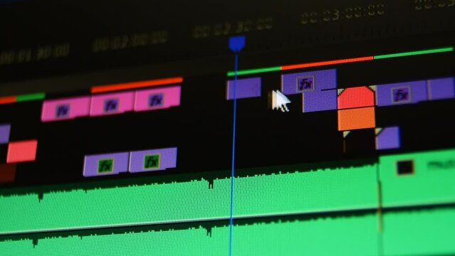 Editing timeline in movie editing software. Macro computer screen. Dolly shot of computer screen in audio video editing software. Moving cutting clips of film music sound. Low depth of field.
