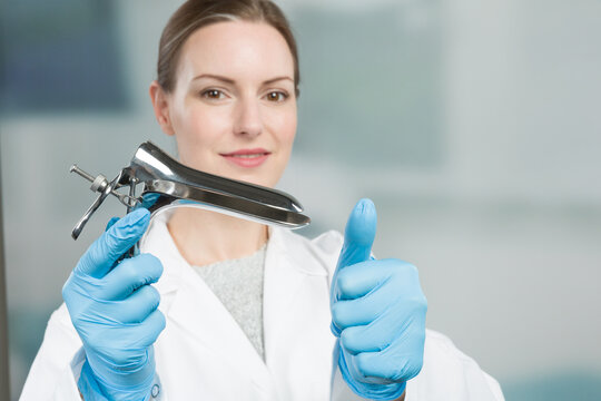 Female gynecologist with a speculum in her hand shows thumbs-up