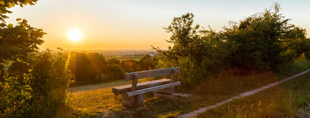 A beautiful sunset late Spring over the rolling hills from south Limburg. The wooden bench is an...