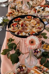 bruschetta with pesto, dried tomatoes, cheese, pomegranate, cheese and pastrami on a black metal tray and a golden lattice stand on the background of a festive table
