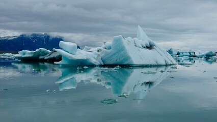 Fototapeta na wymiar Gletscher Fjord und Gletscher Lagune. Kleine Eisstücke und riesige Eisberge - alles mit bewölktem Himmel.
