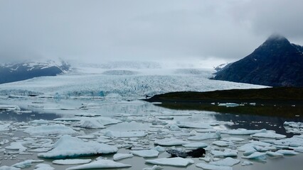 Gletscher Fjord und Gletscher Lagune. Kleine Eisstücke und riesige Eisberge - alles mit bewölktem Himmel.