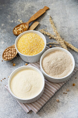 Food and baking gluten free ingredient. Cereals and flours coarse, corn flour, buckwheat flour, chickpeas flour over gray stone background.