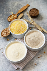 Food and baking gluten free ingredient. Cereals and flours coarse, corn flour, buckwheat flour, chickpeas flour over gray stone background.
