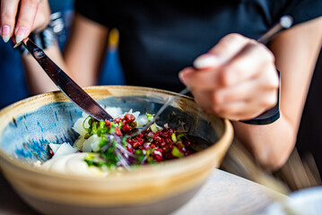 Young woman hand eating beef tartare using knife and fork fom bowl in cafe