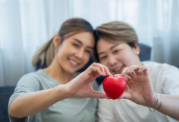 Two asian women lgbtq lesbian homosexual Lesbian couples holding red heart together in living room. homosexuality, valentine's day and love concept