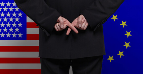 Man standing with crossed fingers against USA and European Union flags background