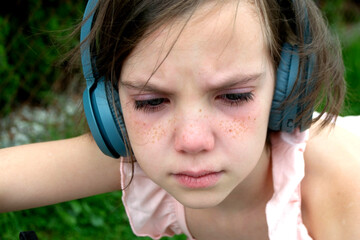 Young beautiful girl fooling around with a branch and wearing headphones on them to listen to music or block out sound due to auditory sensitivity. High quality photo