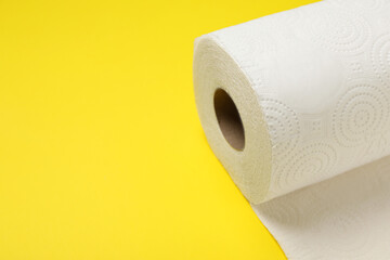 Roll of paper towels on yellow background, closeup. Space for text