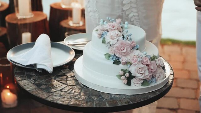 Wedding cake decorated with flowers, pastel pink roses slow motion. Detail of wedding cake cutting by newlyweds.