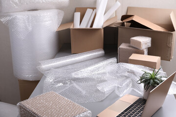 Table with laptop, boxes and bubble wrap in warehouse