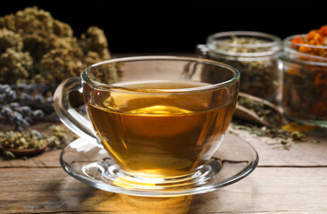 Freshly brewed tea and dried herbs on wooden table