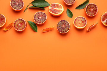 Many ripe sicilian oranges and leaves on orange background, flat lay. Space for text