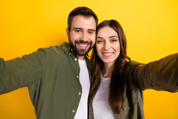 Closeup image of cheerful lovely couple make video vlog of her married life isolated on yellow color background