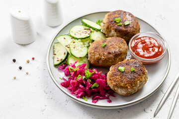 Fried beef rissoles,red cabbage salad, cucumber salad, ketchup. Top view, copy space.