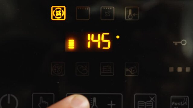 A close-up of the cook reducing the temperature on the oven from 190 to 140 degrees Celsius