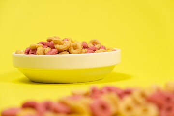 Quick cereal breakfast in the form of rings on a plate on a yellow background