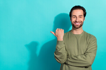 Photo of funky brunet young guy index empty space wear green shirt isolated on teal color background